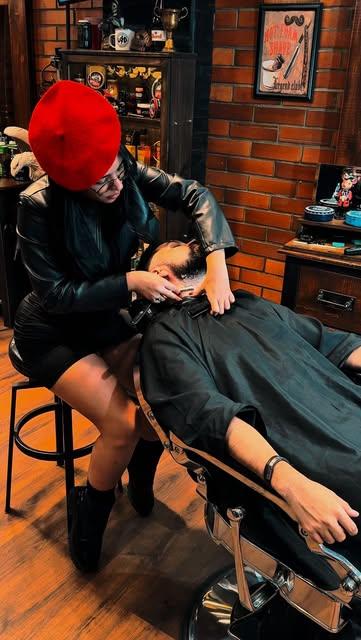 Barbera con boina roja afeitando a un cliente en la silla