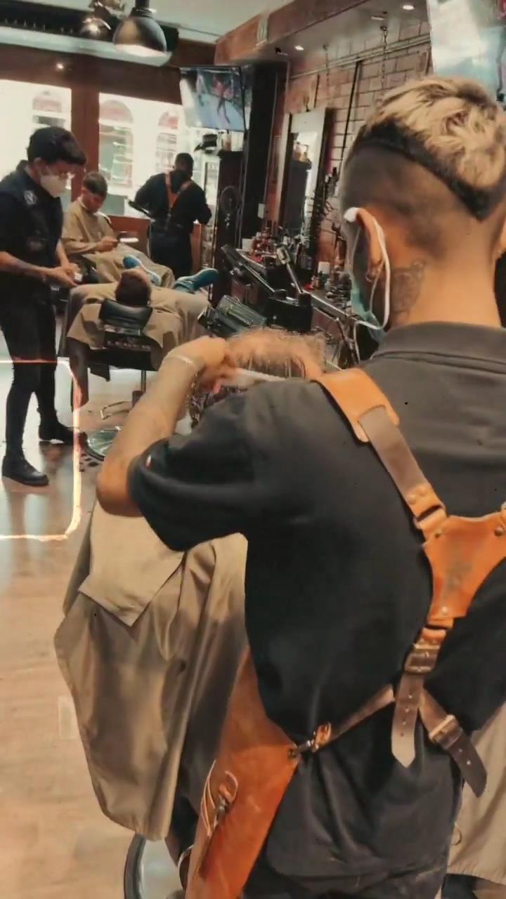 Barbero con delantal de cuero trabajando un corte